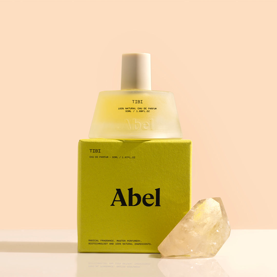 Abel | Tibi | Styled Image_Oct26 - perfume bottle and green box with a crystal on a peach background