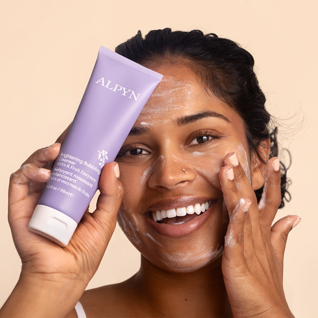 Alpyn Beauty | Brightening Bubbling Cleanser | Model Image - person applying cleanser with foamy lather while holding a lavender cleanser tube