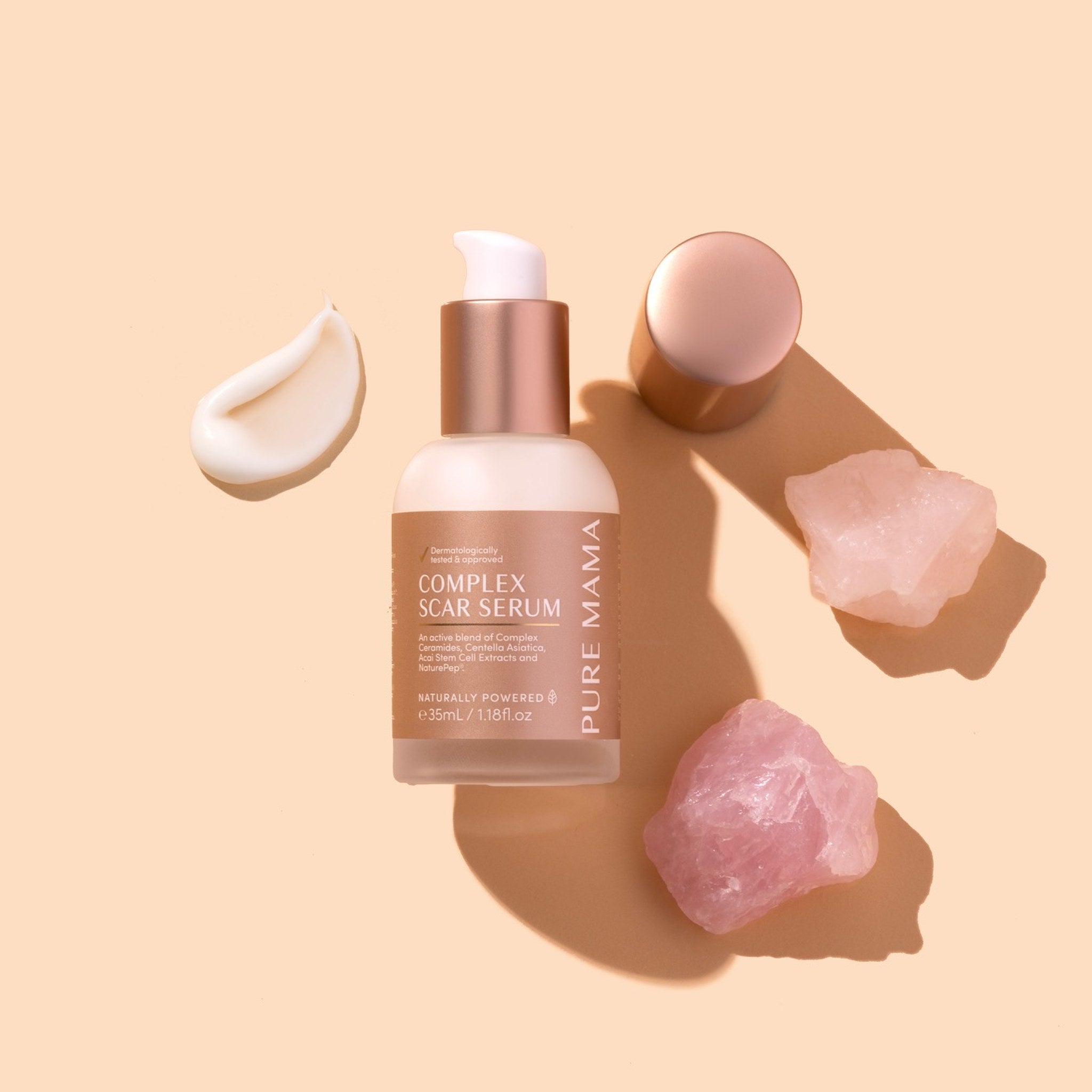 Pure Mama Complex Scar Serum bottle with cream, rose quartz crystal, and white crystal on a beige background