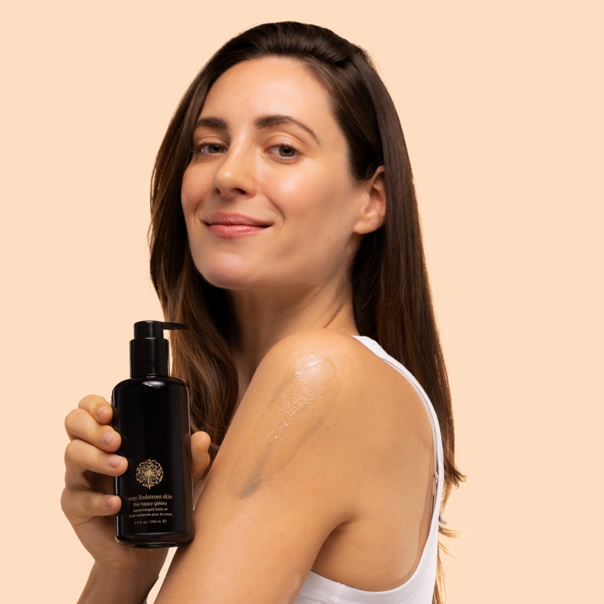 May Lindstrom The Happy Galaxy - model applying to arm, blue serum, while holding black bottle