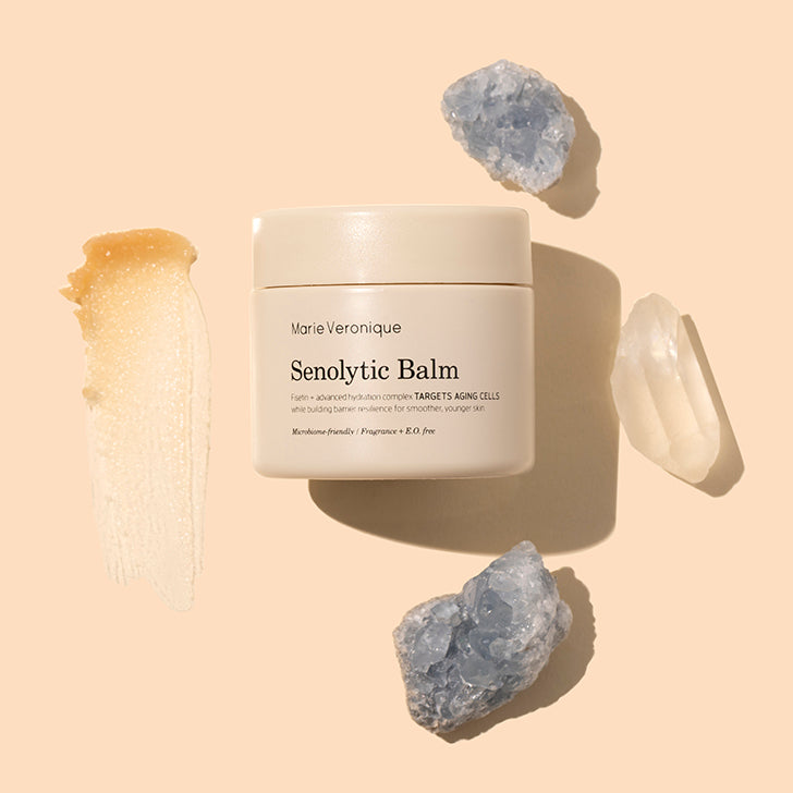 Marie Veronique | Senolytic Balm | Styled image with swatch | Beige jar with orange product swatch on peach background with crystals