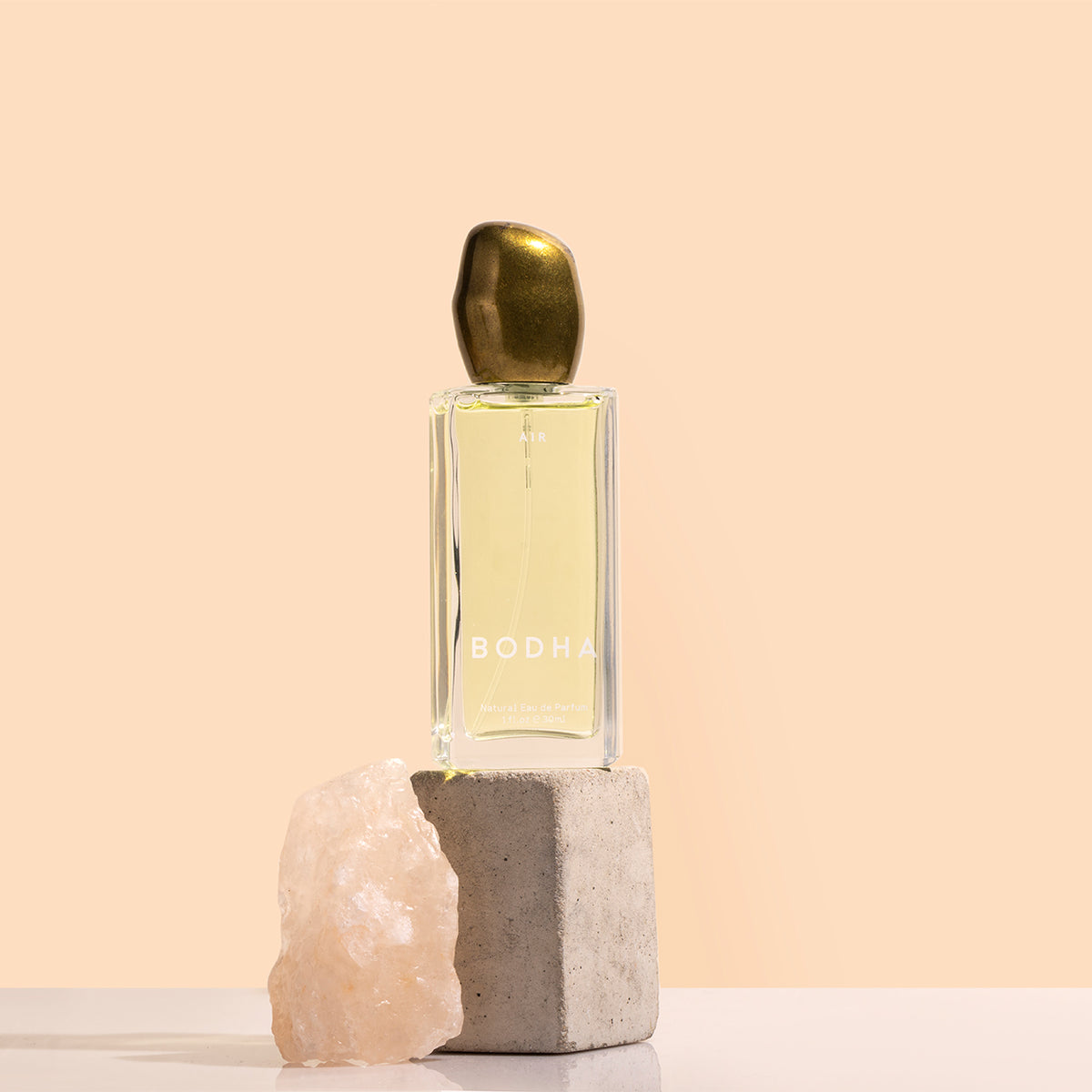 BODHA | Elemental Air Scent | Styled Image_Nov26 - eau de parfum bottle displayed on a stone block beside a pale pink crystal