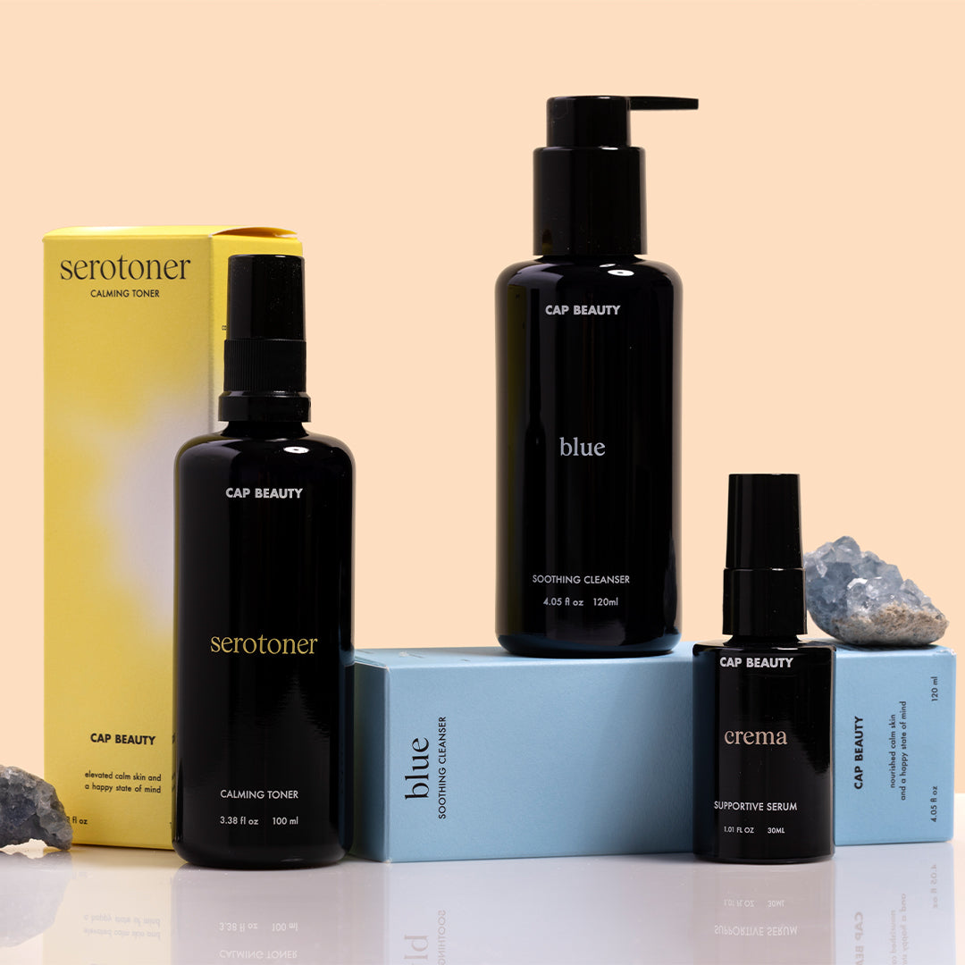 CAP Beauty | Skincare | Group Shot Image - Serotoner, Blue Soothing Cleanser, and Crema Supportive Serum with packaging on a peach background