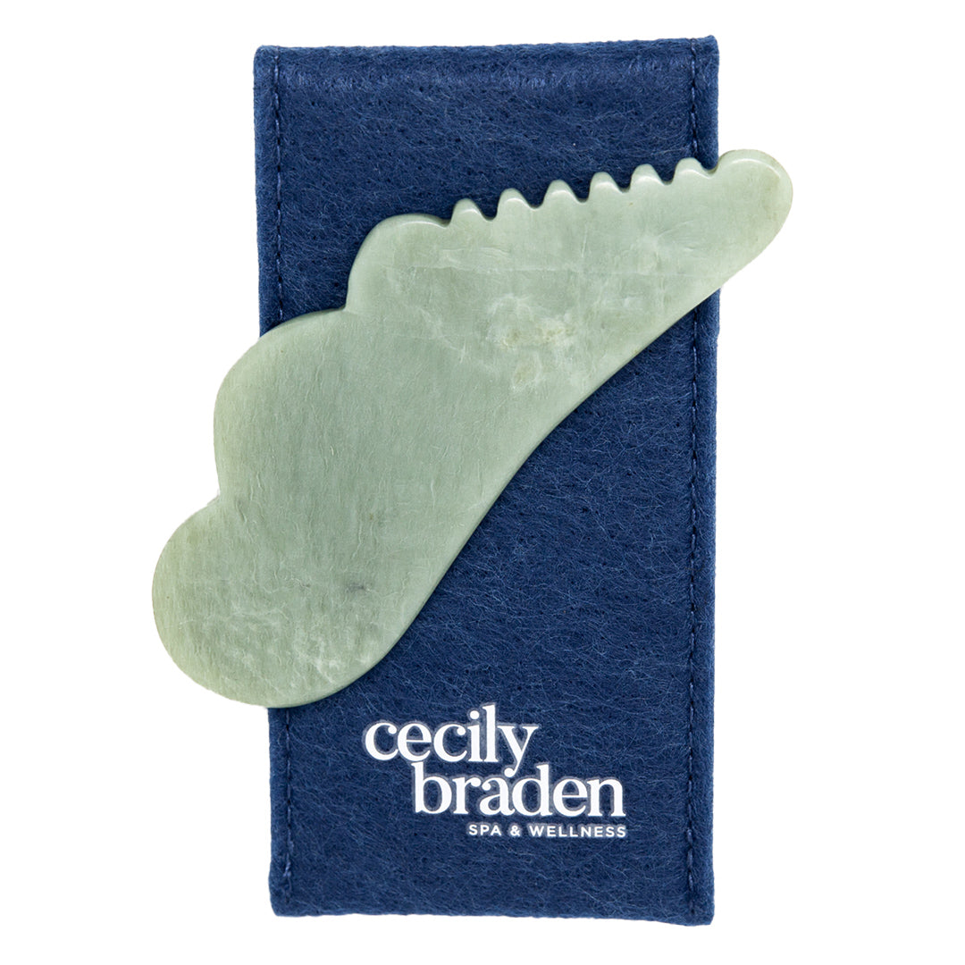 Cecily Braden | Pocket Jade Gua Sha with Ridges | Product Image - light green jade gua sha tool resting on a navy blue Cecily Braden pouch