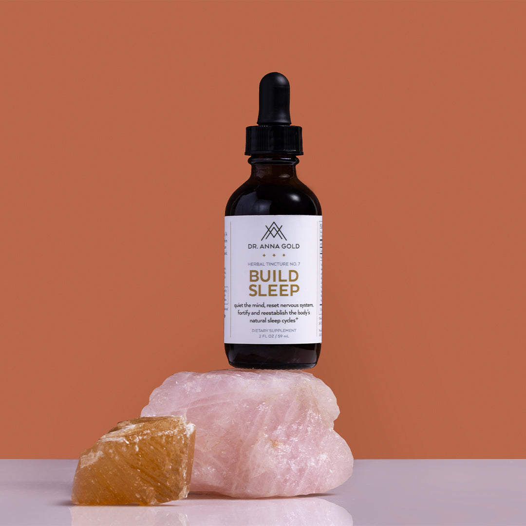 Dr. Anna Gold | Build Sleep | Styled Image_Oct26 - tincture bottle displayed on pink and amber crystals
