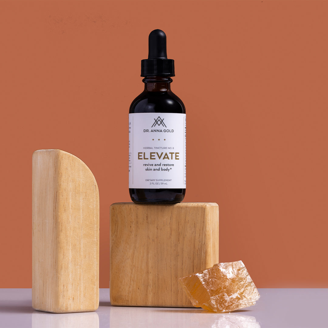 Dr. Anna Gold | Elevate | Styled Image_Oct26 - tincture bottle on wooden blocks with an amber crystal