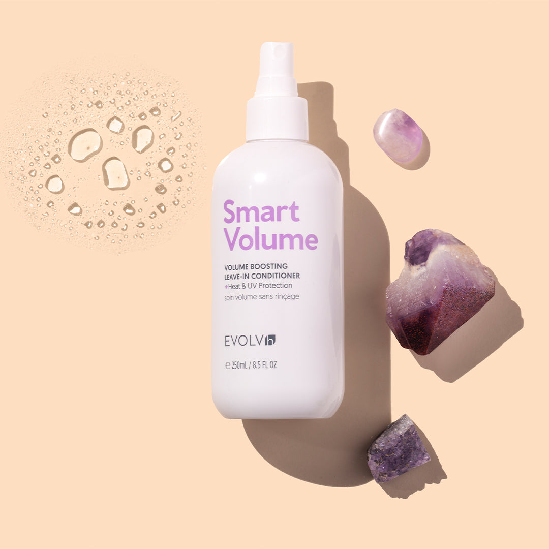 EVOLVh | SmartVolume Volume Boosting Leave-In Conditioner | Styled Image with Swatch_Aug26 - bottle displayed with swatch and purple crystals on a beige background