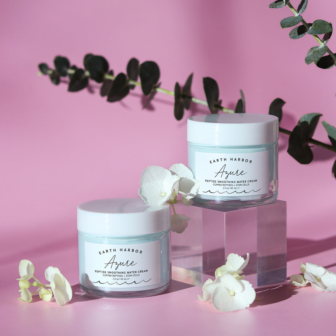 Earth Harbor | Azure Peptide Smoothing Water Cream | Lifestyle Image - two jars displayed with white flowers against a pink background