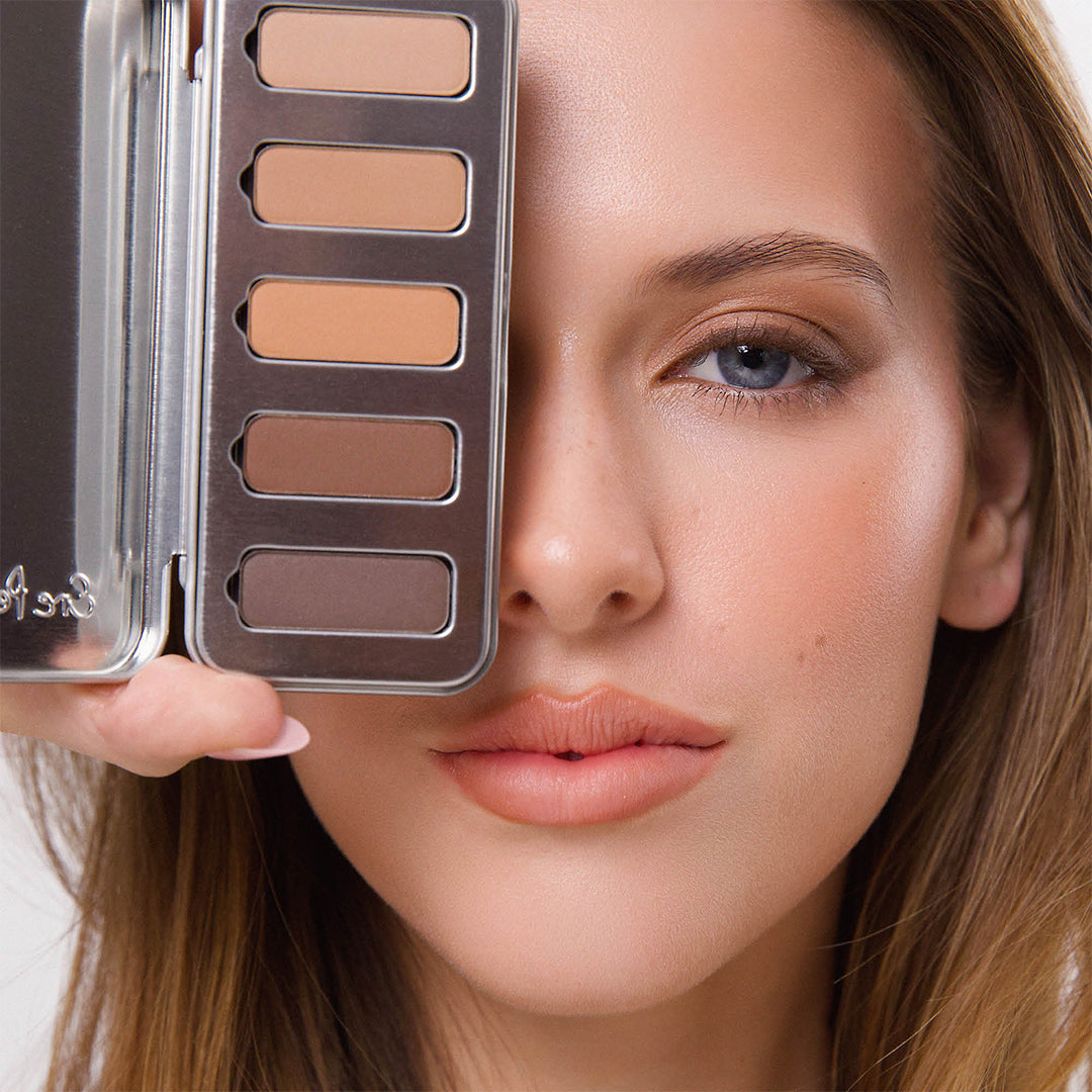 Ere Perez | Chamomile Eye Palette Element Matte | Model Image - model wearing neutral brown eye makeup while holding the open eye palette beside her face