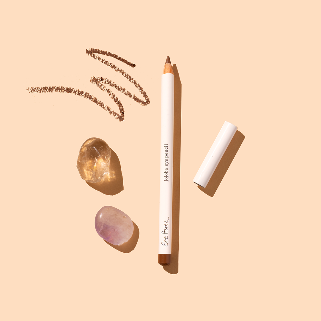 Ere Perez | Jojoba Eye Pencil | Product Image with Swatch - eye pencil with cap, brown swatches, and crystals on a beige background