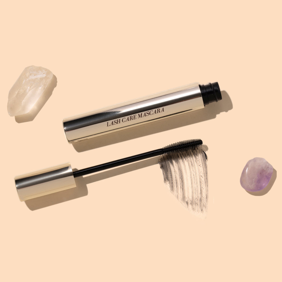 Fitglow Beauty | Lash Care Mascara | Styled Image - black mascara wand, black swatch, and crystals on a peach background