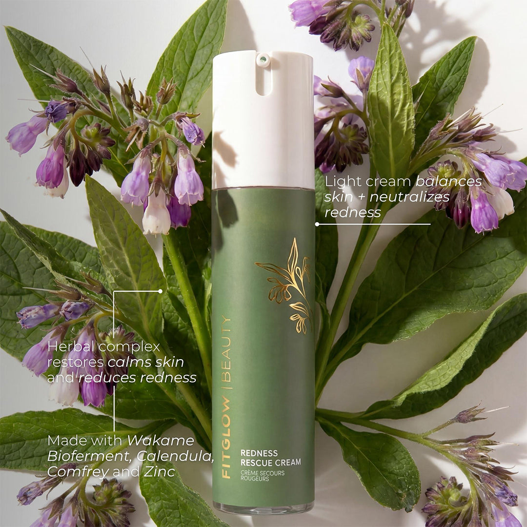 Fitglow Beauty | Redness Rescue Cream | Benefits Image - green bottle surrounded by green leaves and purple flowers on a white background