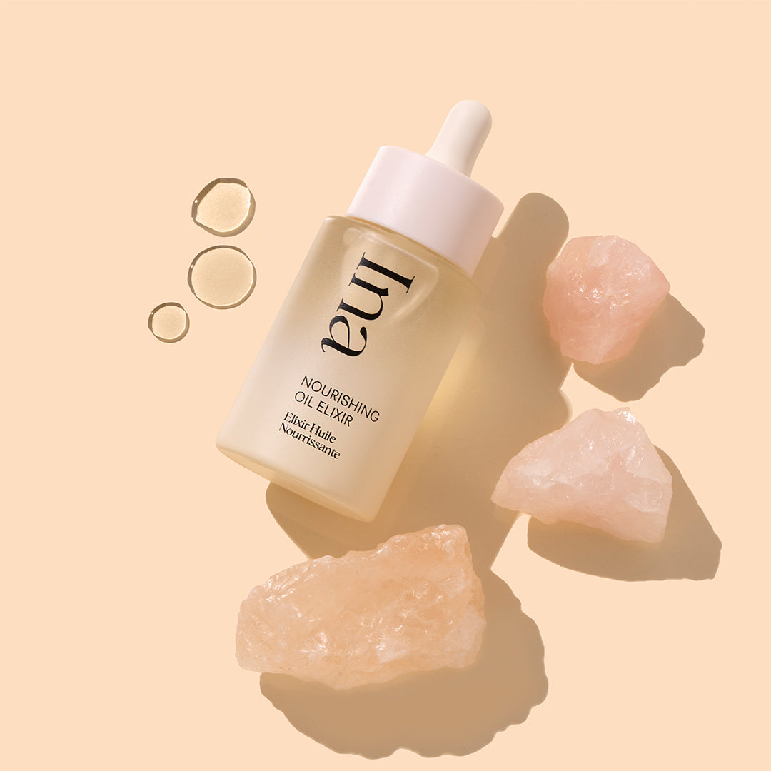 Ina | Nourishing Oil Elixir | Product Image with Swatch - oil dropper bottle with oil drops and pink stones on a beige background