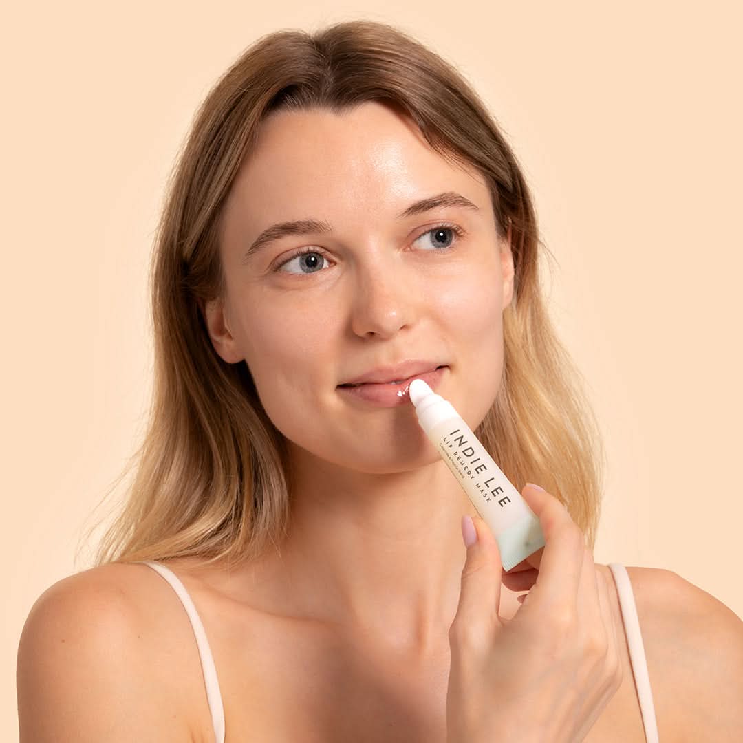 Indie Lee | Lip Remedy Mask | Model image, model applying lip product tube to lips