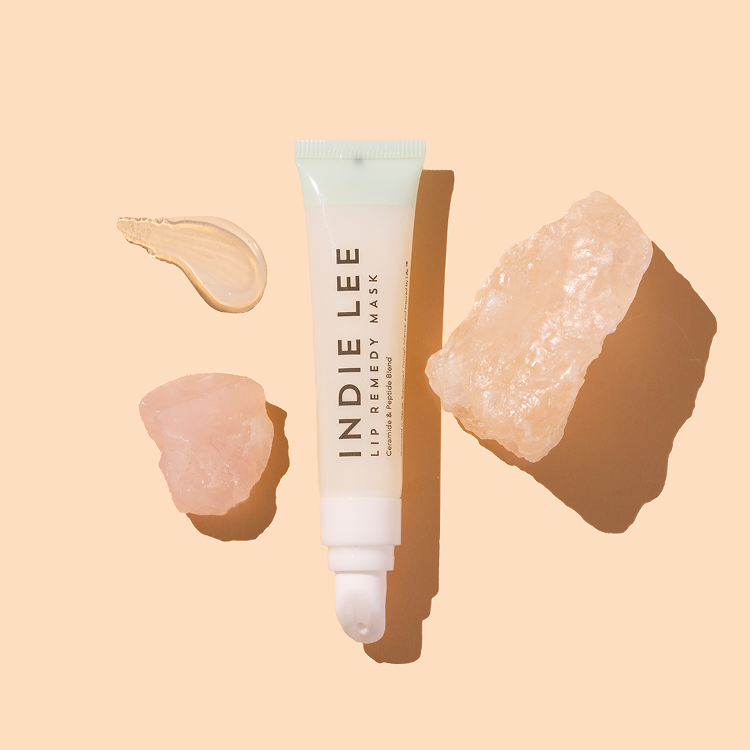 Indie Lee | Lip Remedy Mask | Product Image with Swatch - lip tube with glossy swatch and crystals on a beige background