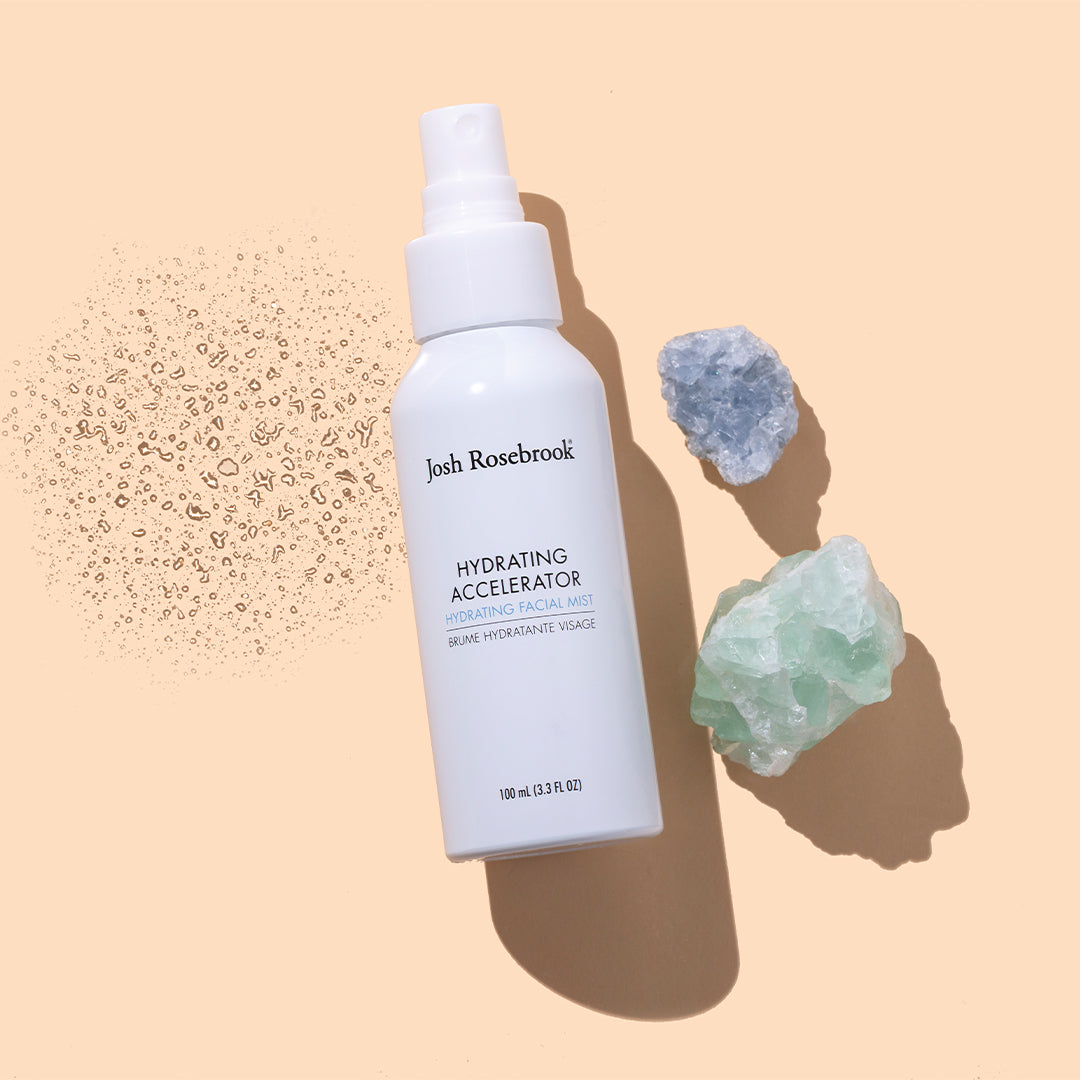 Josh Rosebrook | Hydrating Accelerator | Styled Image with Swatch - white spray bottle displayed on a beige background alongside crystals and a fine mist texture