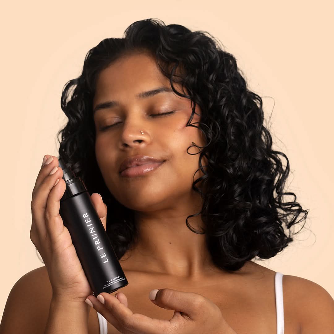 Le Prunier | Plum Spritz | Model Image - person holding facial mist with eyes closed against a beige background
