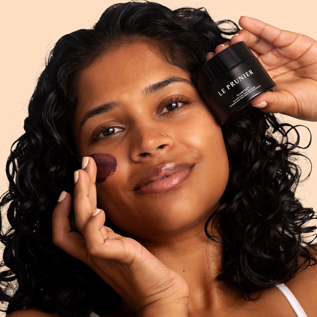 Le Prunier | Plumtox Clarifying Enzyme Mask | Model Image - person applying mask while holding a black jar