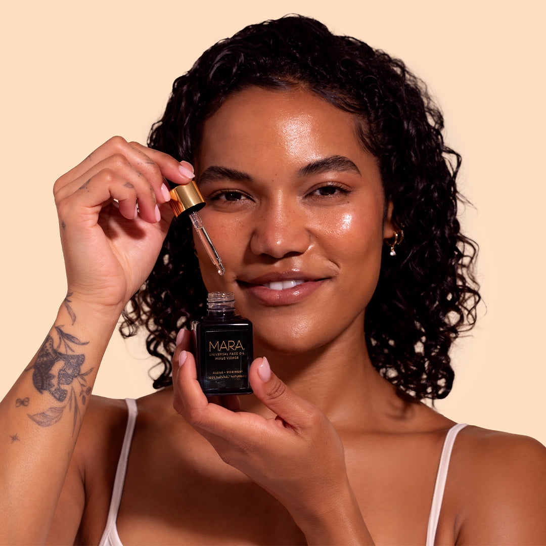 MARA | Universal Face Oil | Model Image_Jul26 - model holding an open bottle of oil with the dropper raised above the bottle
