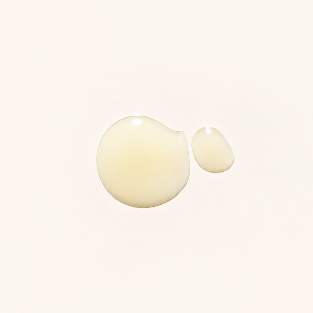 Marie Veronique | Senolytic Serum | Texture Image - two drops of golden serum on a light cream background