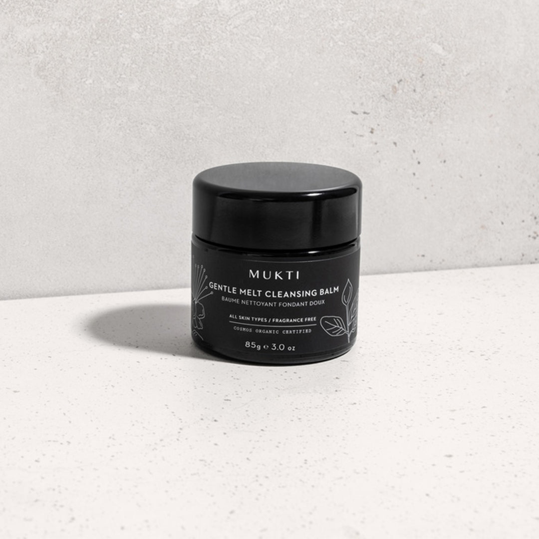 Mukti | Gentle Melt Cleansing Balm | Product Image2 - black jar on a light textured surface