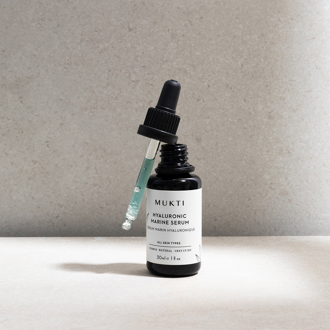 Mukti Organics | Hyaluronic Marine Serum | Lifestyle Image - bottle with dropper displaying the light blue serum texture