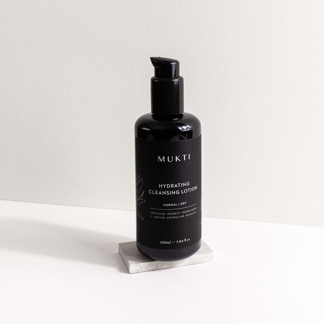 Mukti Organics | Hydrating Cleansing Lotion | Lifestyle Image - black pump bottle displayed on a white stone surface