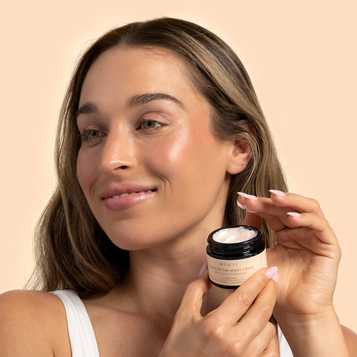 Mukti | Queen of the Night Creme | Model Image | Model holding black jar with white creme scooped onto fingers