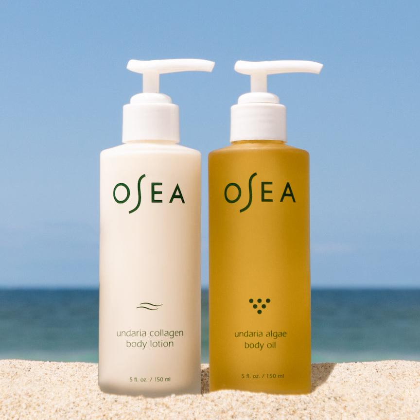 OSEA | Undaria Body Bestsellers | Body Lotion and Oil - body lotion and body oil standing together on sand with the ocean in the background