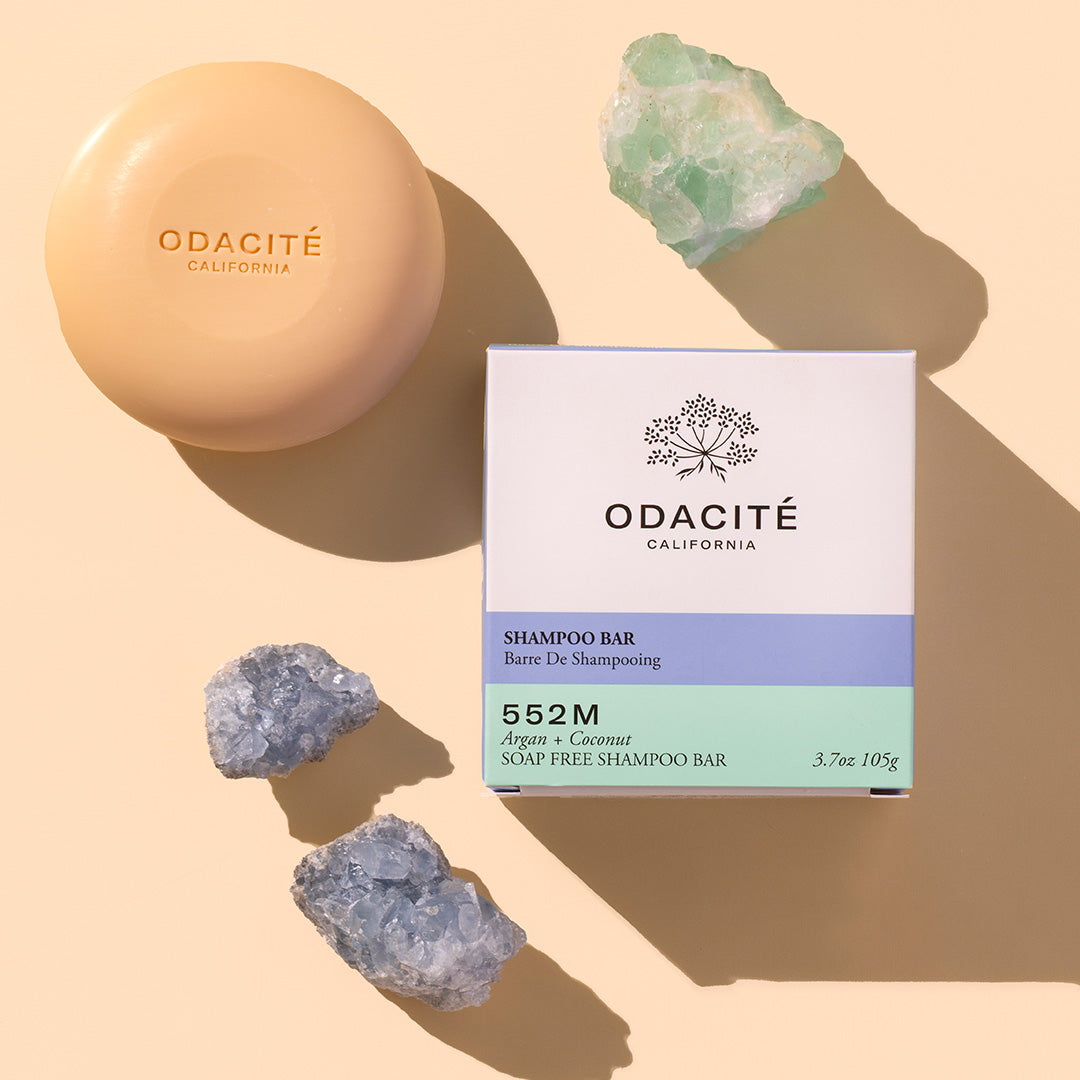 Odacite Shampoo Bar 552m Styled Image, yellow/beige shampoo bar, round laying on beige/peach background with white square box labeled Odacite