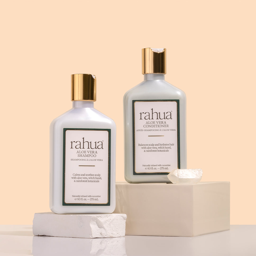 Rahua | Aloe Vera Shampoo and Conditioner | Product Image - 2 bottles with gold cap and crystal against a beige background