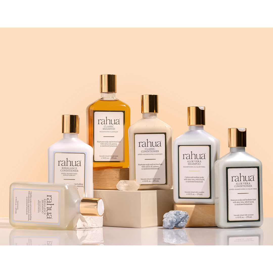 Rahua | Group Shots | Product Image - 6 bottles with gold cap beside each other with crystals against a beige background