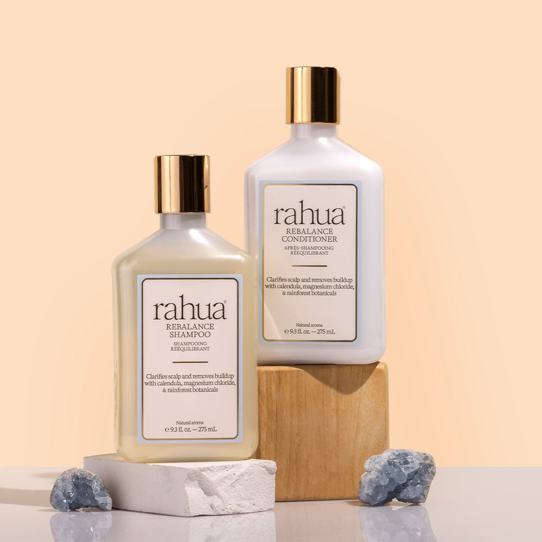 Rahua | Rebalance Shampoo and Conditioner | Styled Image_Oct26 - 2 bottles with gold cap beside each other with crystals against a beige background