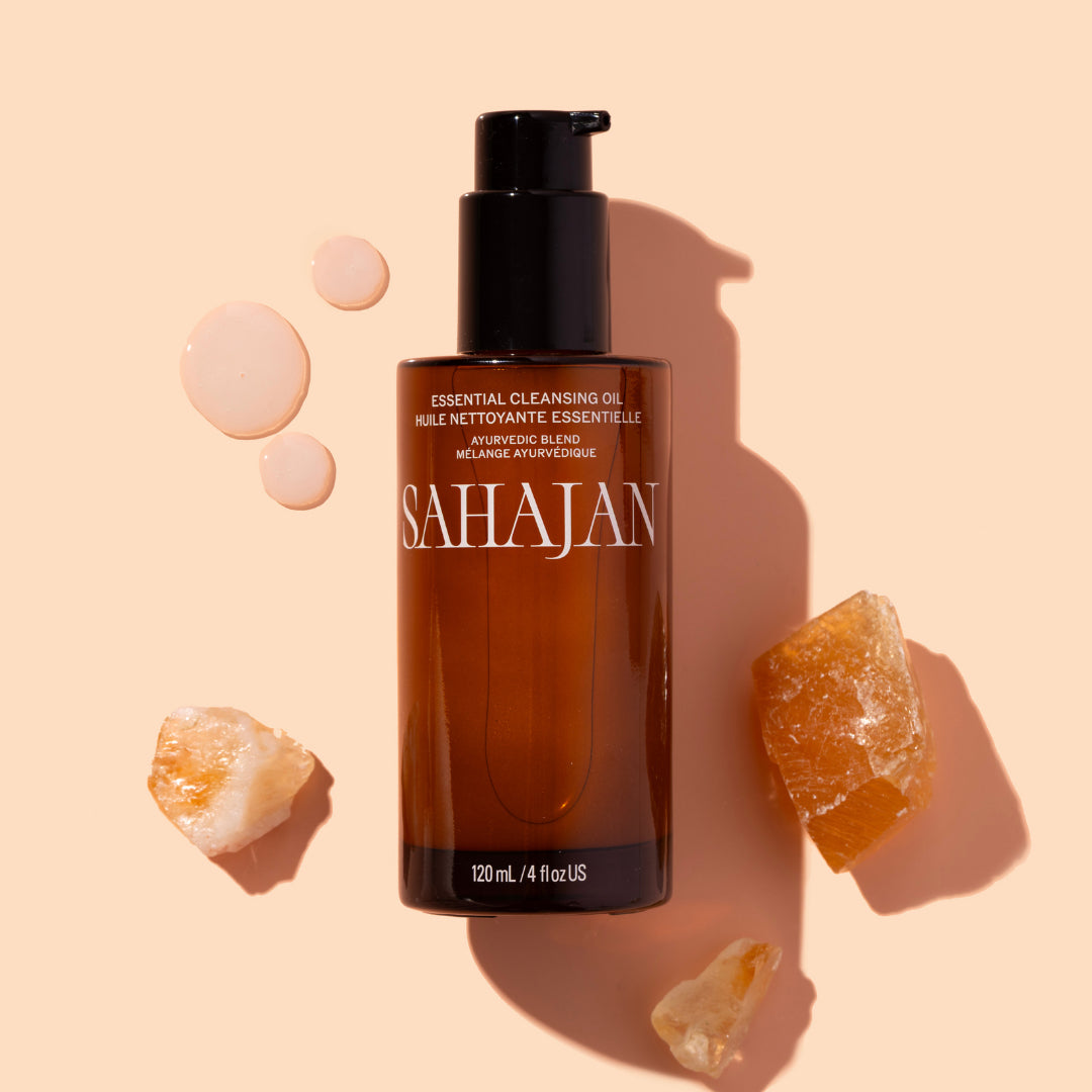 Sahajan | Essential Cleansing Oil | Styled Image with Swatch - cleansing oil bottle styled with droplets and crystal stones on a beige background