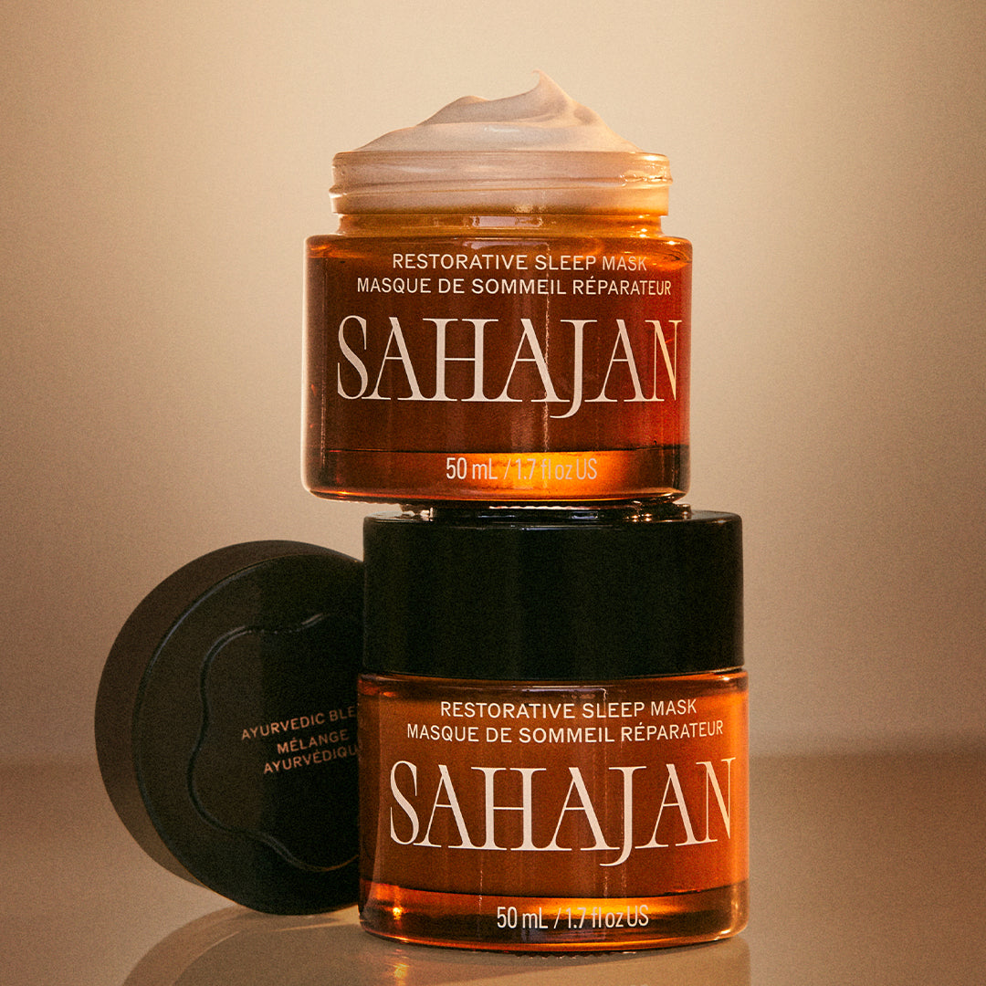 Sahajan | Restorative Sleep Mask | Lifestyle Image - two jars displayed on a warm beige background, with one jar open to reveal the creamy mask texture and the lid placed beside it