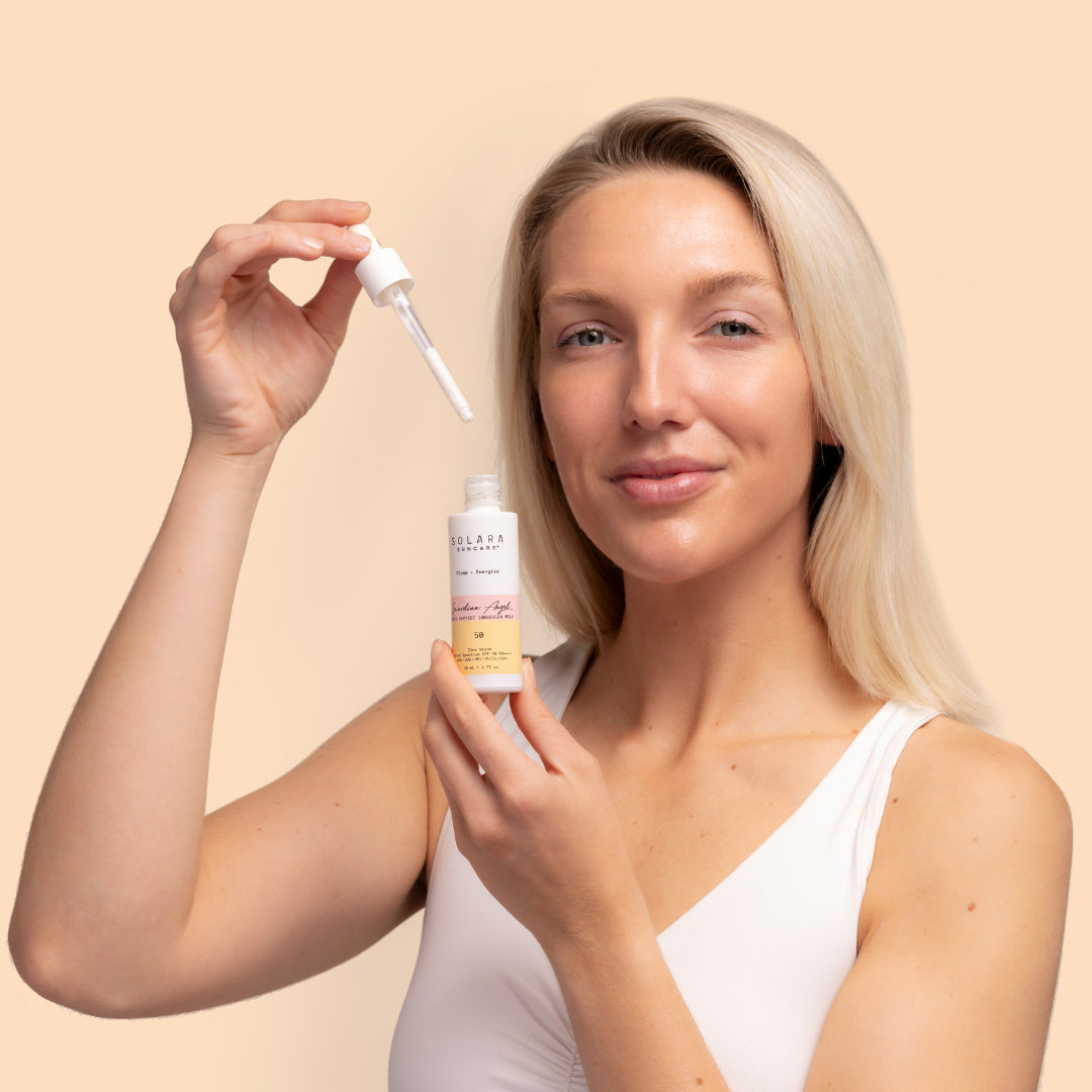 Solara Suncare | Guardian Angel Super Peptide Sunscreen Milk, SPF50 | Model Image - a woman holding a dropper against a neutral background