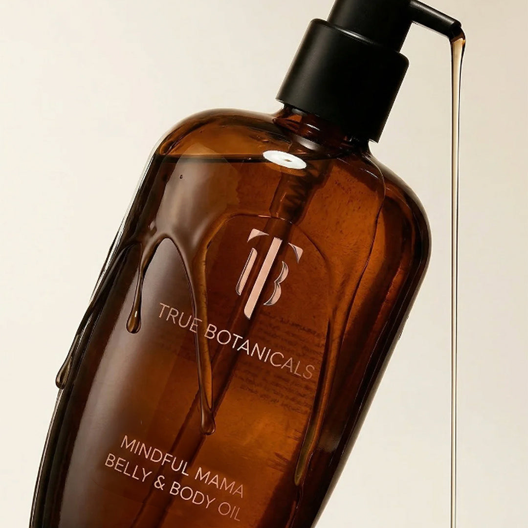 True Botanicals | Mindful Mama Belly & Body Oil | Close-up Image - amber glass bottle with black pump dispensing oil