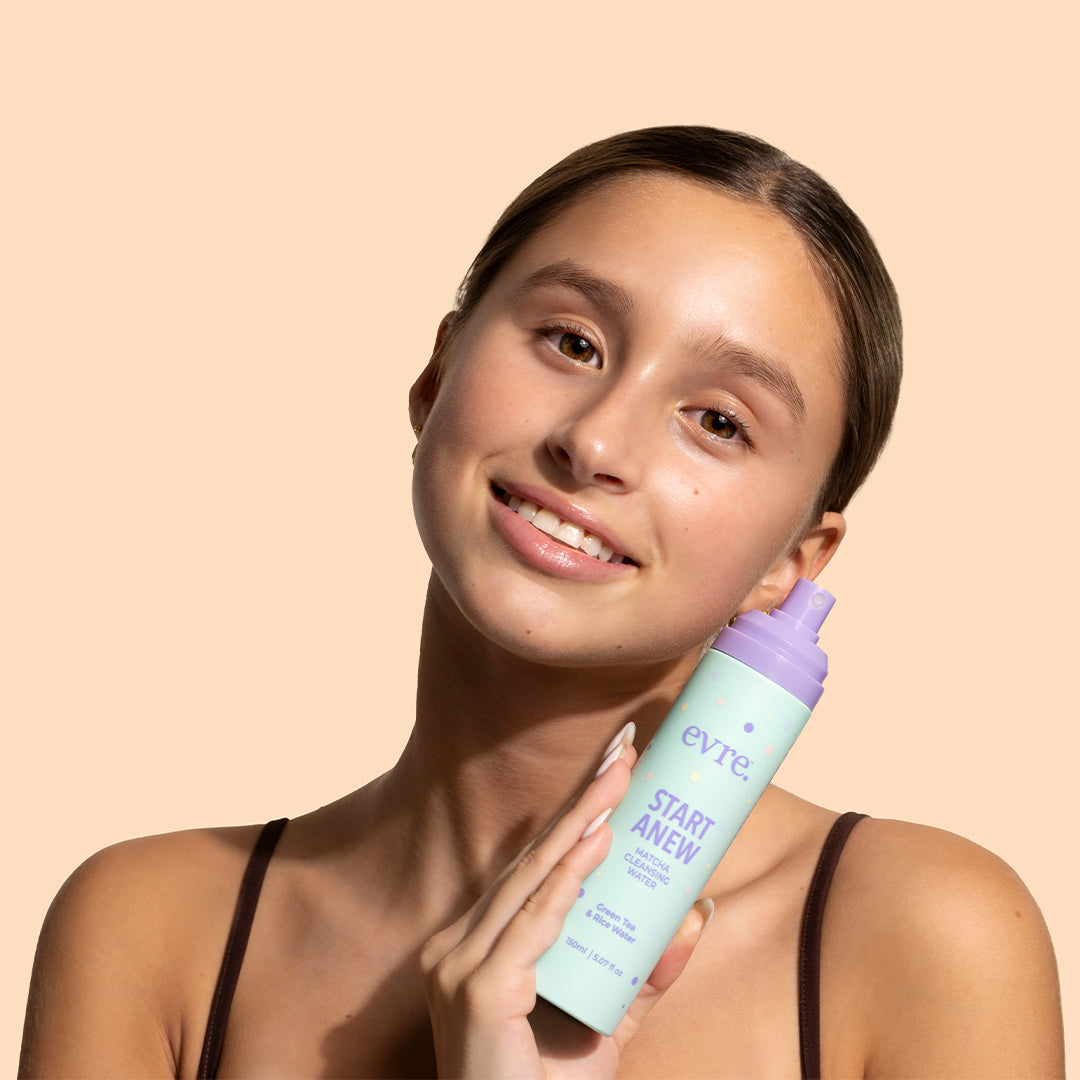 evre. | Start Anew Matcha Cleansing Water | Model Image2 - model holding a mint green bottle with lavender pump against a peach background