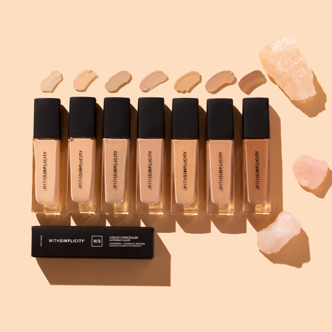 withSimplicity | Liquid Concealer | Product Image - shade range displayed in multiple tones with swatches above, styled on a beige background with crystals