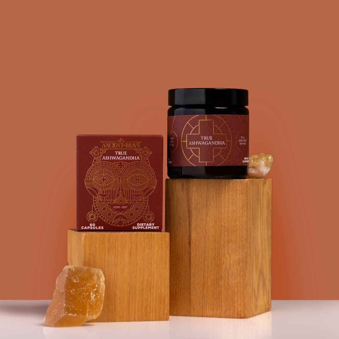 Ancient + Brave | True Ashwaganda | Product Image with Box - jar and box displayed on wooden blocks with crystals on a warm brown background
