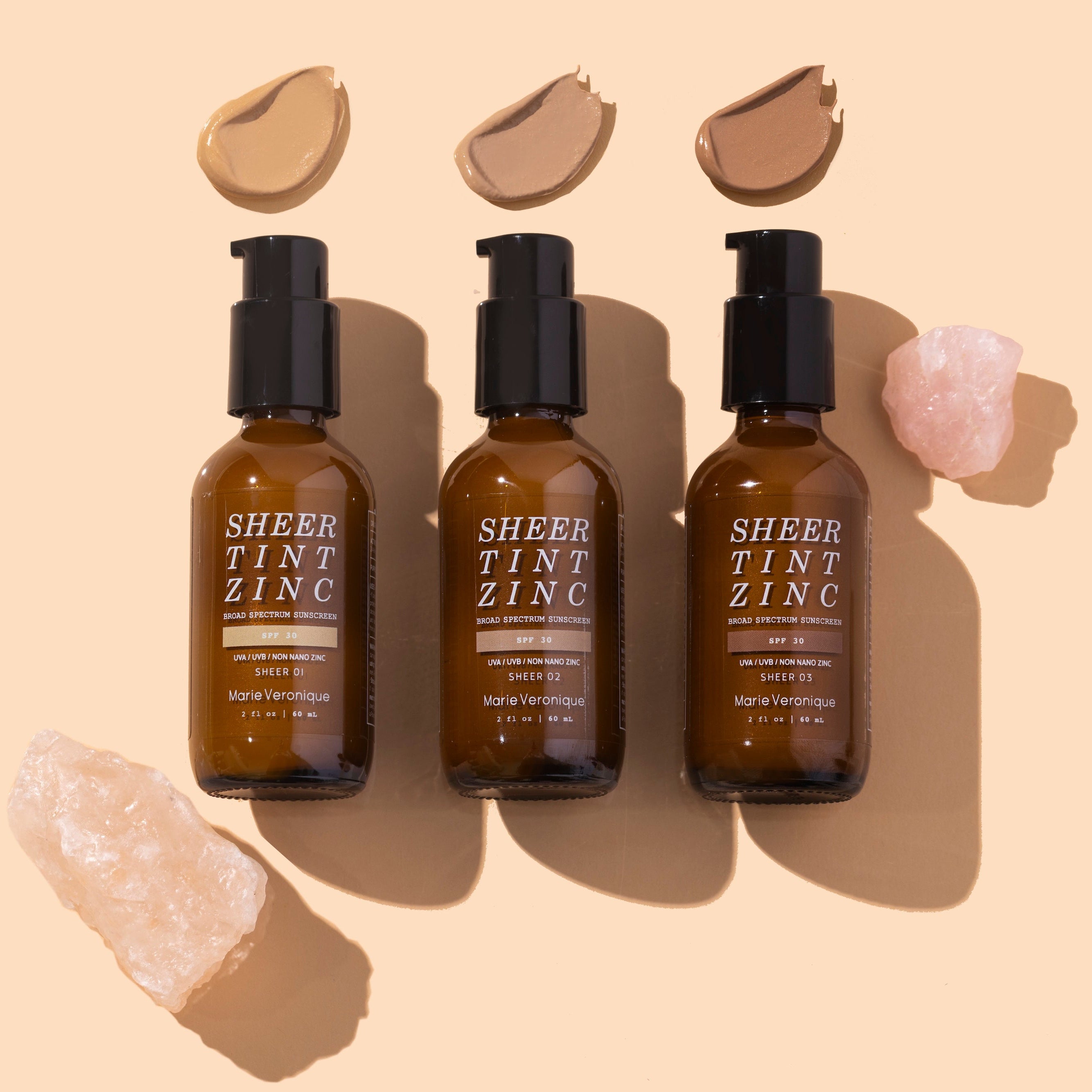 Marie Veronique | Sheer Tint Zinc | Flat lay image with swatch, brown bottles on peach background with  product swatches 