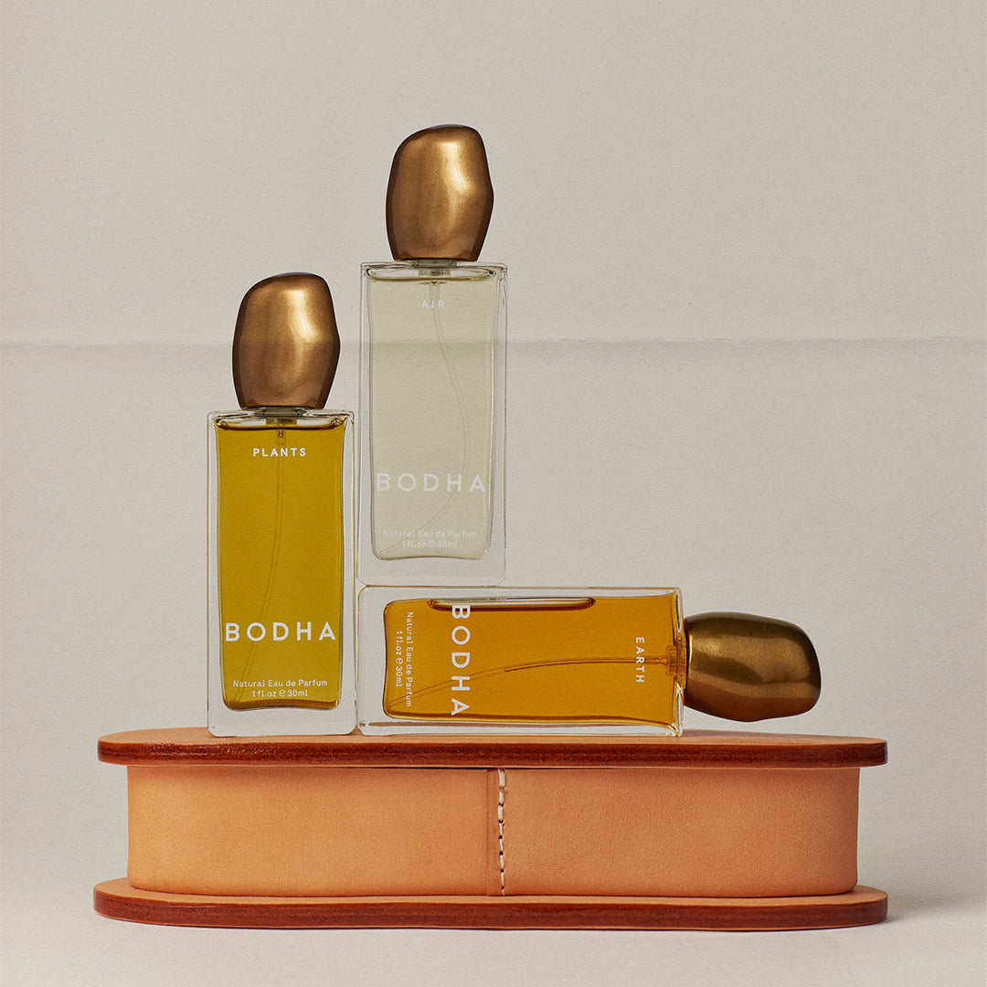 BODHA | Elemental Eau de Parfum | Collection Image - three parfum bottles in Air, Plants, and Earth arranged on a tan leather case