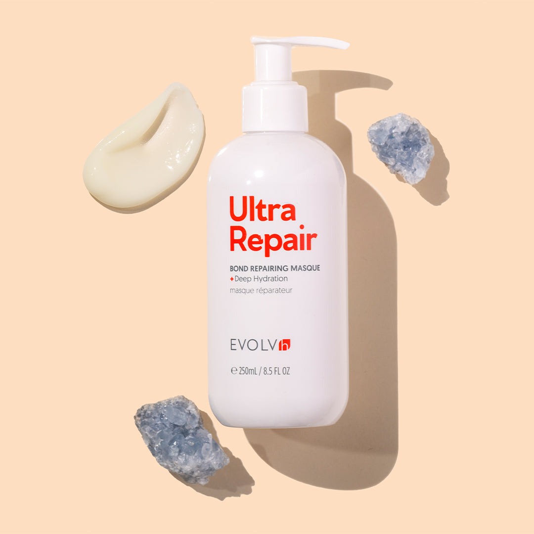EVOVLVh | UltraRepair Bond Repairing Masque | Styled Image with Swatch_Aug26 - white bottle displayed with a cream swatch and crystals on a beige background