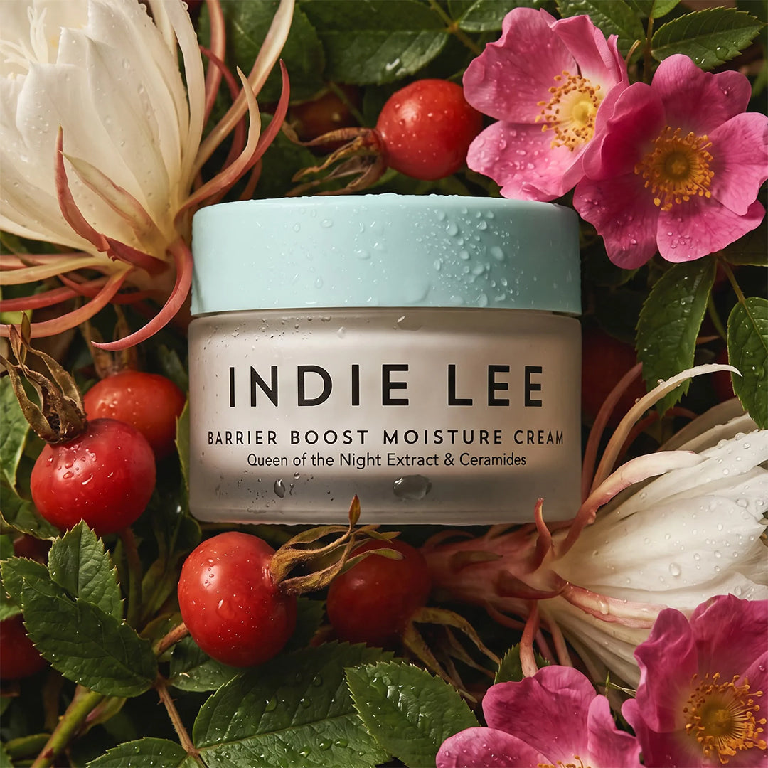 Indie Lee | Barrier Boost Moisture Cream | Lifestyle Image - jar surrounded by Queen of the Night flowers, rosehips, and pink blossoms