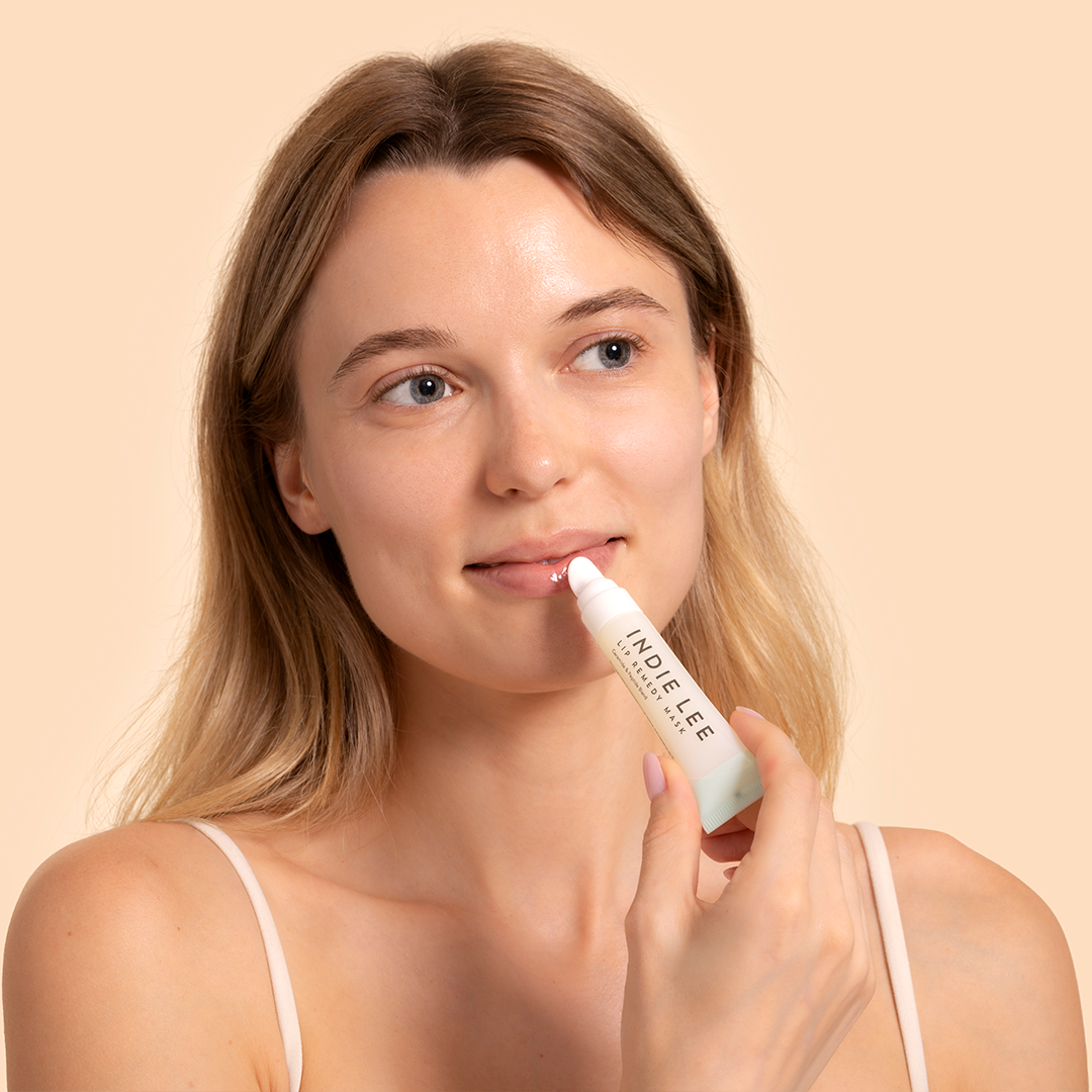 Indie Lee | Lip Remedy Mask | Model Image - woman applying lip mask against a beige background