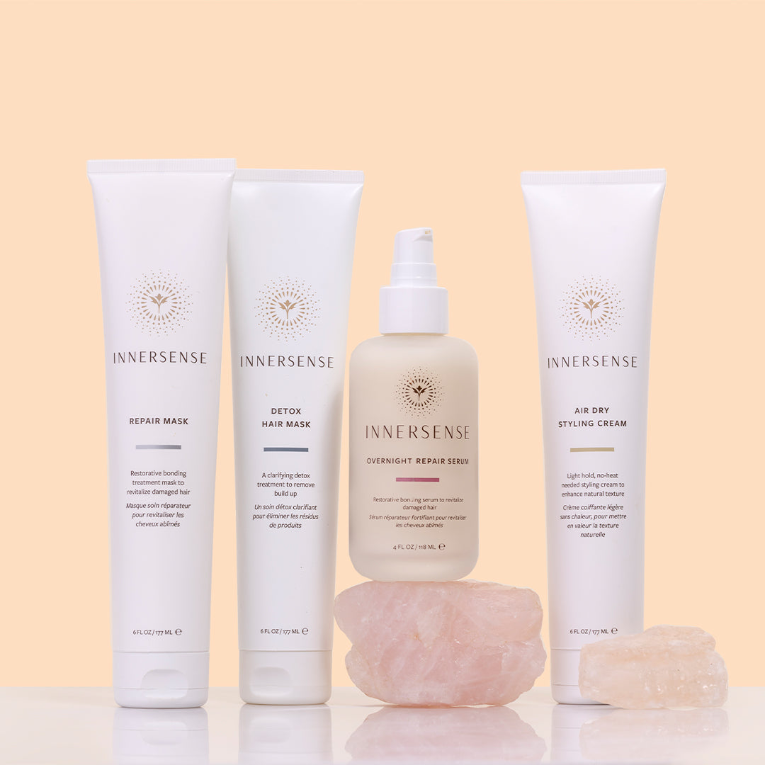 Innersense Organic Beauty | Discovery Box Collection | Styled Image - hair care collection featuring Repair Mask, Detox Hair Mask, Overnight Repair Serum, and Air Dry Styling Cream displayed with rose quartz crystals on a soft beige background 