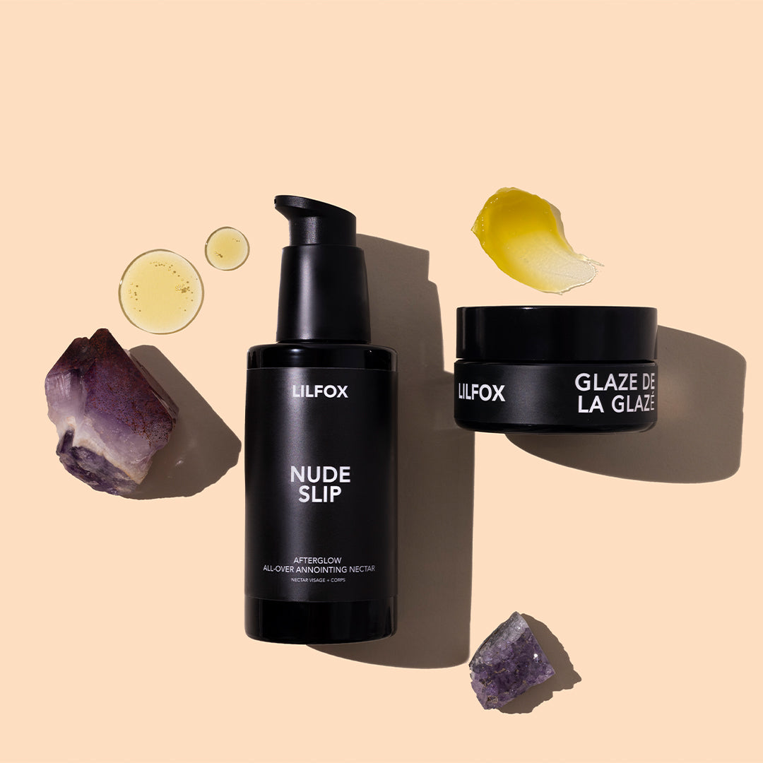 LILFOX | Nude Slip and Glaze de la Glazé | Styled Image - black pump bottle and black jar with golden product swatches and purple crystals on a peach background