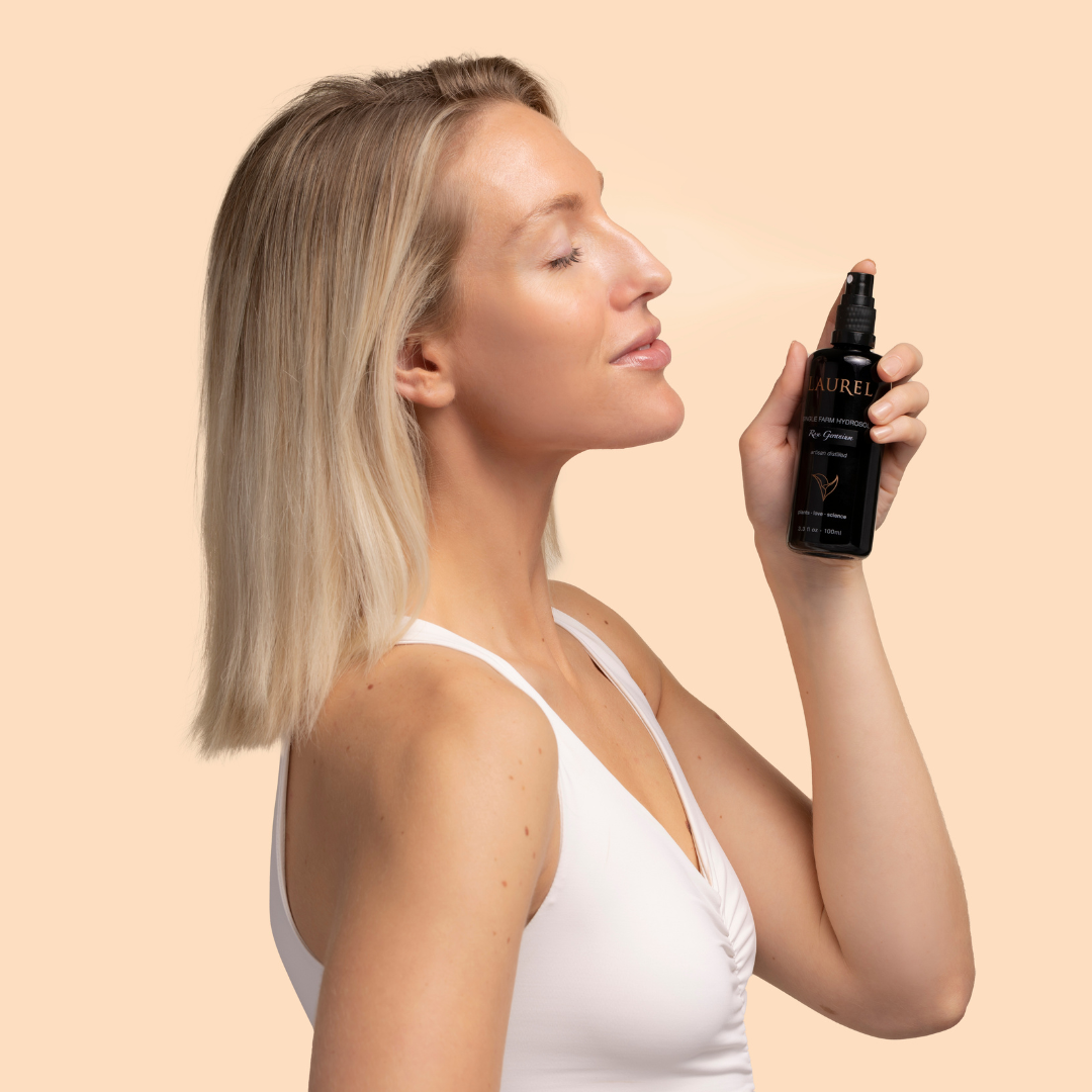 Laurel Skin | Rose Geranium Single Farm Hydrosol | Model Image - a woman holding a bottle near her face, eyes closed, against a neutral background