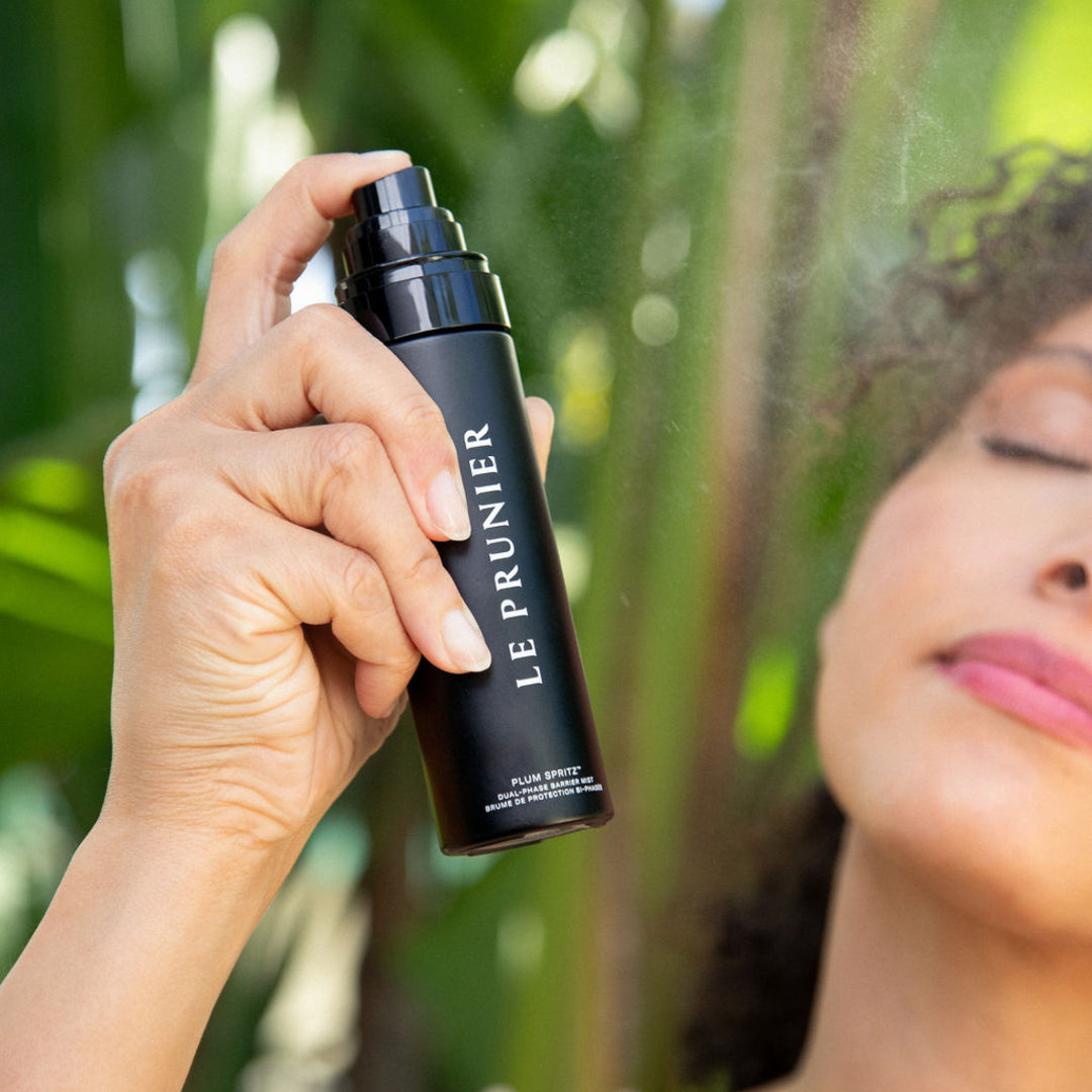 Le Prunier | Plum Spritz Dual-Phase Barrier Mist | Model Image - mist beside a model with eyes closed against a lush green background