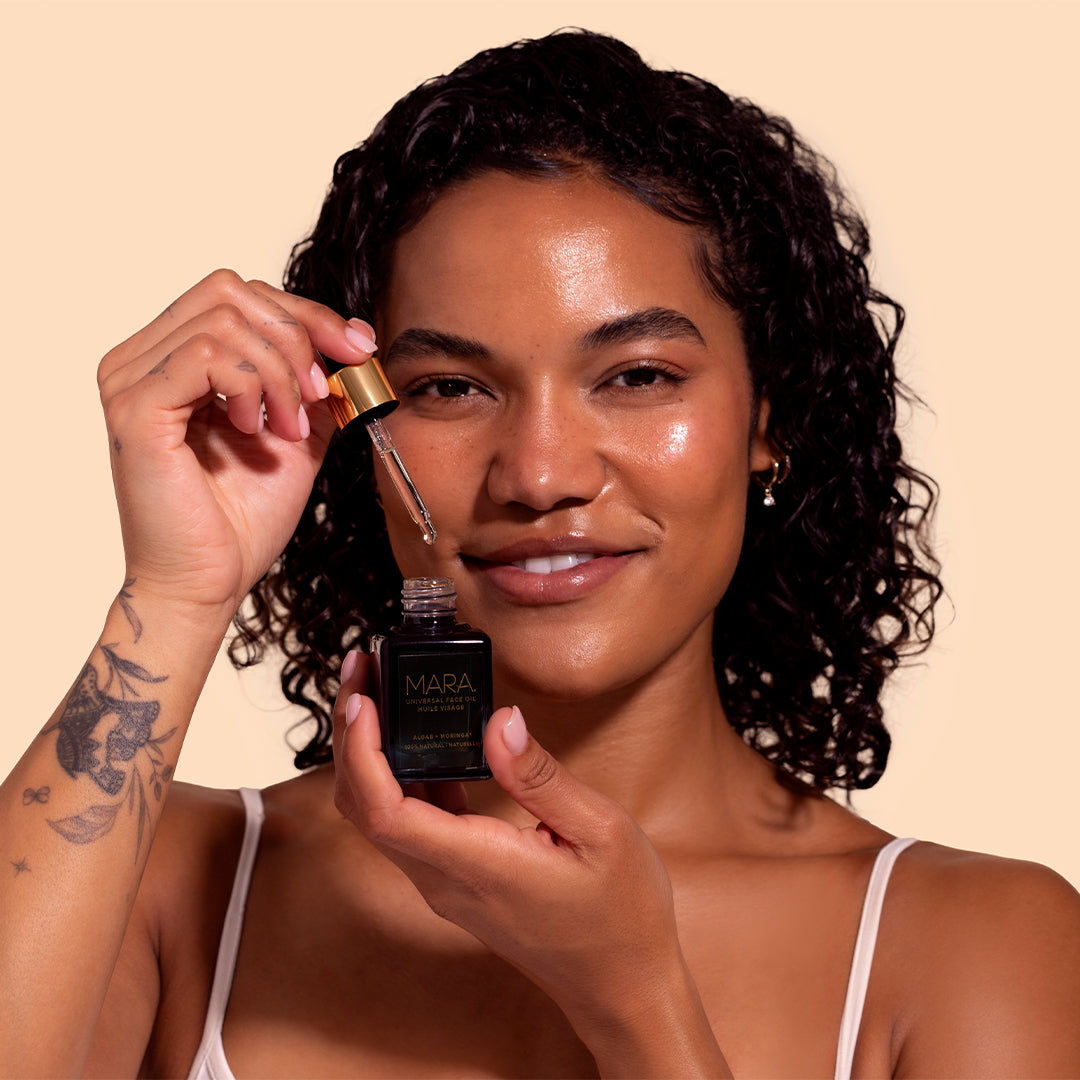 MARA | Universal Face Oil | Model Image_Jul26 - model holding an open bottle of oil with the dropper raised above the bottle